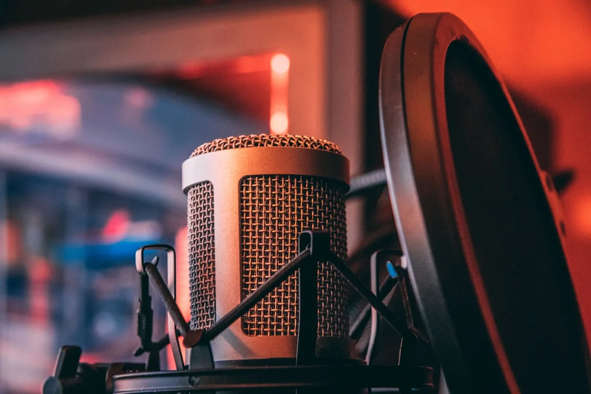 Externt audio interface anslutet till mikrofon och studiohörlurar på ett skrivbord.